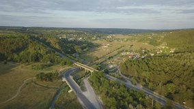Aerial view on highway road through green fields on a summer sunny day. 4k footage of landscape with asphalt freeway between meadow and rural field. Drone shoots video.
