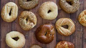 Grabbing a Bagel from a Variety of Bagels on a Wooden Table