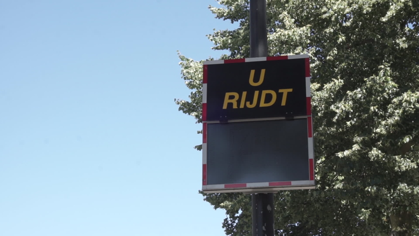 Roadside speedometer warning sign with dutch text "You are driving..." on the top and an green and red speed indication at the bottom