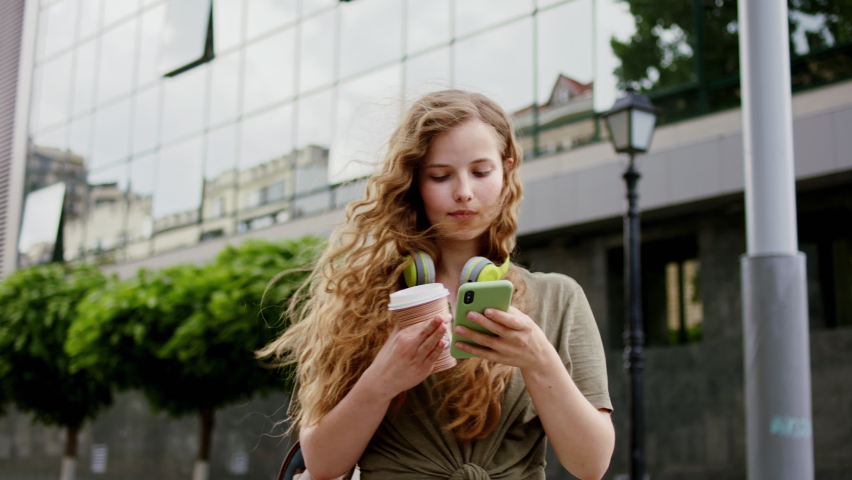 Very beautiful with a long hair lady walking down the street smiling large and speaking on her smart phone