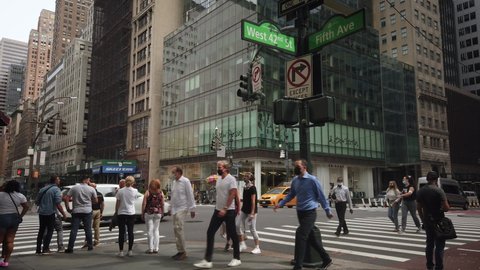 New York  USA - Sep 9, 2020: 42nd Street and 5th Avenue Manhattan during Coronavirus pandemic. People crossing street with face masks and social distancing. Yellow taxi cab crossing intersection.