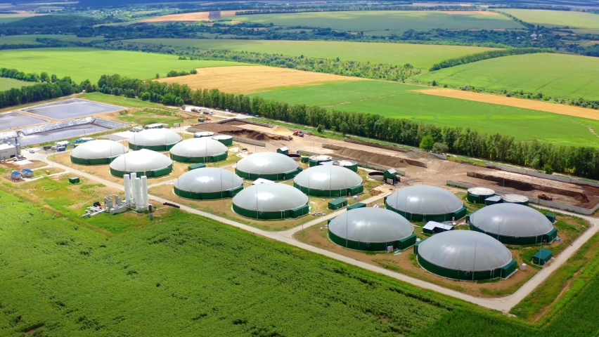 Biogas plant surrounded by nature. Modern storage tanks on biogas farm on field. Renewable energy from biomass. Aerial view. Royalty-Free Stock Footage #1058923301