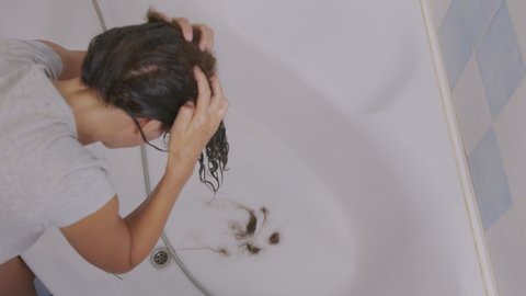 Hair problems. The girl's hair falls out into the sink while washing.