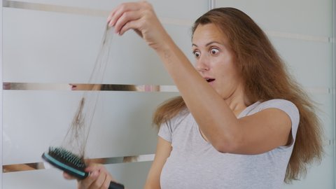 Woman brushing hair with hairbrush, worrying about hair loss shedding or bad condition. Upset woman hair loss.