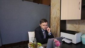 Eating during a video call. A man in a business suit is talking via video communication. There is food and alcohol on a tray nearby