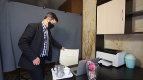 Eating during a video call. A man in a business suit removes the mask from his face and talks via video link. Communicating, he drinks coffee. Nearby on a tray is a coffee maker and a muffin