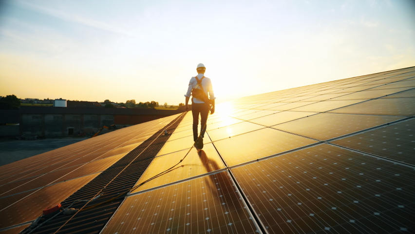 Maintenance assistance technical worker in uniform is checking an operation and efficiency performance of photovoltaic solar panels on roof at sunset. clean green energy, sun power  Royalty-Free Stock Footage #1058929211