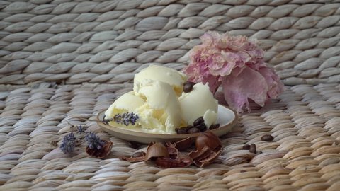 Shea butter on a plate on a white background with lavender flowers and nuts shell.
