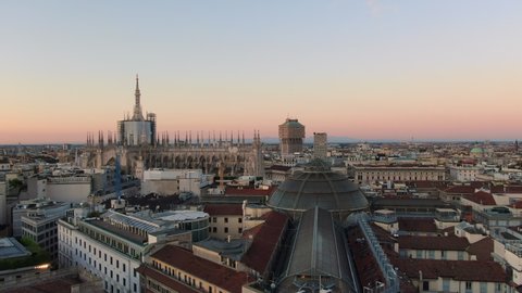 aerial shot of milan city center at dawn,drone moving up over vittorio emanuele gallery at sunrise revealing duomo cathedral