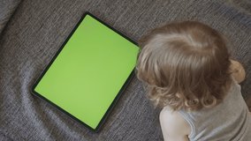 Toddler kid watches green screen tablet display 4K footage