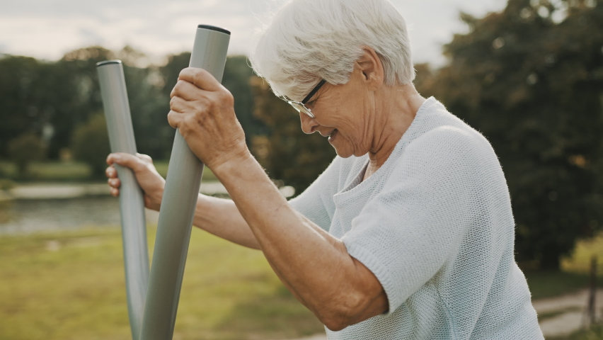 Old woman exercising in and outdoor gym. Slow motion. High quality 4k footage Royalty-Free Stock Footage #1058942753