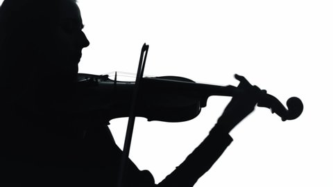 Young woman playing violin in white studio. Musician with an instrument. Silhouette