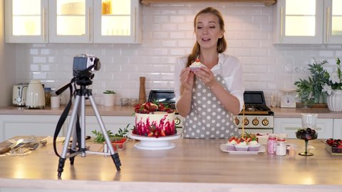 Blogger pastry chef makes a video lesson about cooking a cake. young woman in an apron at home in the kitchen tells the recipe on camera. Online broadcast, author leads a blog or course about cooking.