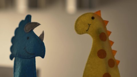 A triceratops and stegosaurus finger puppets dancing together