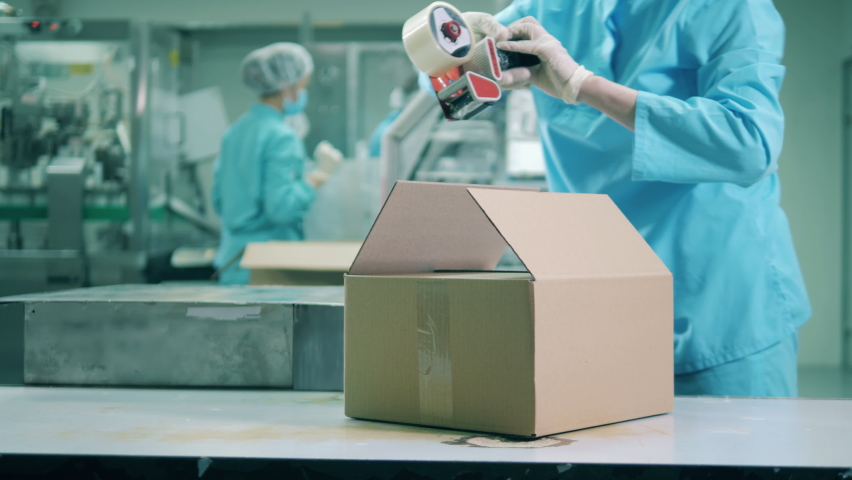 Pharmaceutics worker is closing a box with a duct tape Royalty-Free Stock Footage #1058949080