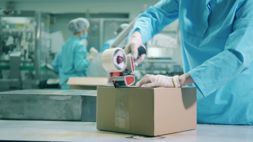 Pharmaceutics worker is closing a box with a duct tape | Shutterstock HD Video #1058949080