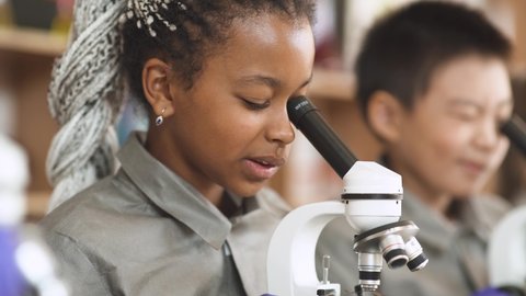 Lesson in a modern school, kids look at microscopes and communicate in a chemistry lesson, the process of teaching children and biology in a modern school.