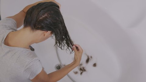Hair problems. The girl's hair falls out into the sink while washing.