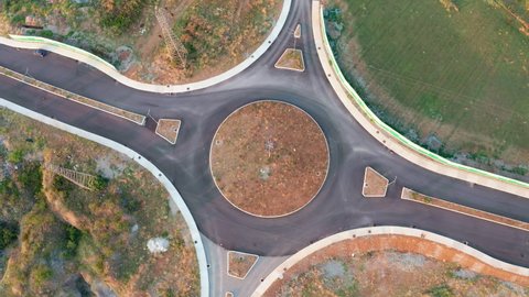 Roundabout junction on an empty road in the middle of nowhere. No traffic on the circular intersection under construction and street in an uncultivated field.