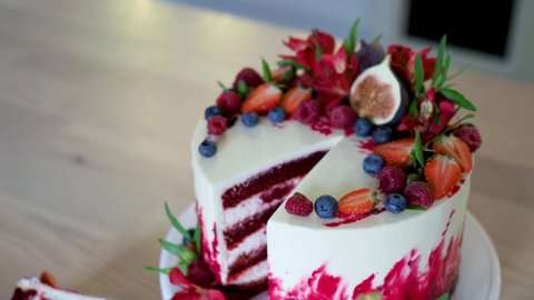 Big beautiful red velvet cake, with flowers and berries on top. Slice on a plate, dessert. Cake and muffins, sweet holiday treats.