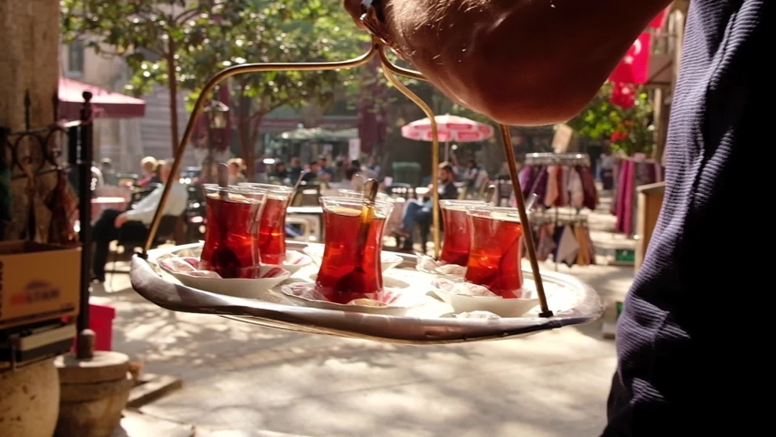Turkish tea on a tray. Waiter carrying set of glasses with tea in traditional outdoor tea garden. Close up shot of full tea tray in slow motion. | Shutterstock HD Video #1058953070