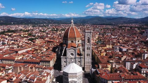 Aerial view of Cathedral of Santa Maria del Fiore zooming out with city and mounatins on a sunny day in Florence in Italy in 4k.