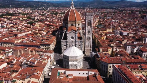 Aerial view of Cathedral of Santa Maria del Fiore flying and zooming in with city and mounatins on a sunny day in Florence in Italy in 4k.