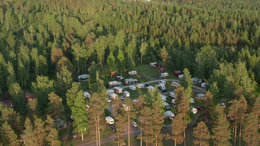 Camping ground in forest. Aerial drone view of caravan motor home camp site in beautiful evening light. Surrounded by nature and green woods in clean environment. Royalty-Free Stock Footage #1058959358