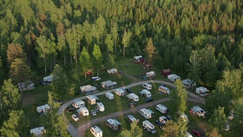 Camping ground in forest. Aerial drone view of caravan motor home camp site in beautiful evening light. Surrounded by nature and green woods in clean environment.