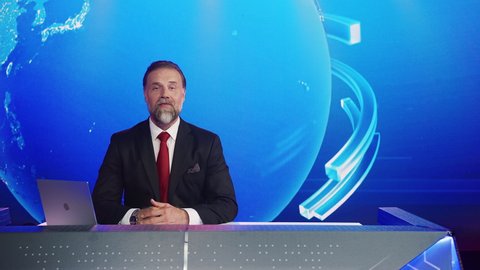 Live News Studio with Professional Male Anchor Reporting on the Events of the Day. Mock-up Television Channel Newsroom Set with Presenter Newscaster Talking. Globe Graphics Background. Static Shot