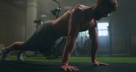 Man doing push ups in a gym. Exhaling and inhaling after push-ups and exercise. Perfect for fitness and workout. Young sports man performs pushups in the gym. The athlete is engaged in fitnes