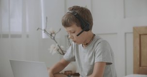 little boy is talking to someone by online video call, using notebook with internet and headphones, staying home at vacation