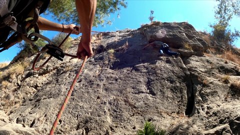 Barcelona, Spain, September 10, 2020. One sportsman mountain climbing while other secure the rope. Physical activity in the countryside. Risky sports. Mountain climb.