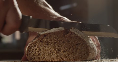 Cutting with a Knife Crusty Artisan Bread in the Kitchen on a Sunny Day Shot on Red Camera