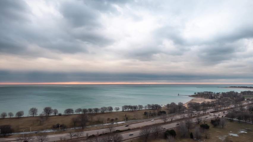 Chicago, IL - March 14th, 2019: Heavy fluffy white and blue clouds float over the water of Lake Michigan and the vehicular traffic of a busy Lake Shore Drive on the North side of the city at sunrise.