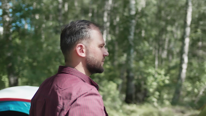 Traveler standing near a tent site campground on a seashore. Summer sunny day. Summer landscape background. Camping in a forest. Parallax high quality 4k footage