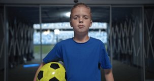 Portrait of Young little boy near the field with soccer ball. Football professional training, talented kids, motivational video. Children player on professional stadium.