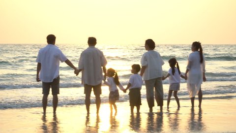 group of asian multi generation family running on beach silhouette in sunset or Sunrise on vacation in thailand
