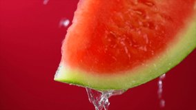 Fresh Watermelon slice over red background. Slice of ripe watermelon with dripping juice, close-up. Vegan food, diet concept. Slow motion 4K UHD video.