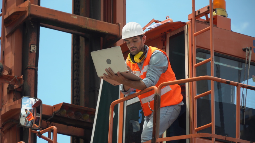 Foreman holding laptop computer checking loading Containers box on cabin crane at warehouse logistic in Cargo freight ship for import export. engineer at high construction site  Royalty-Free Stock Footage #1058967851