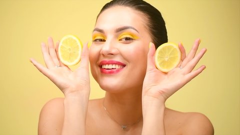 Healthy eating, diet. Beautiful healthy girl with slices of lemon citrus fruit, food, cosmetics. Beauty young fashion woman plays with lemons, organic vegetables. Vegetarian concept. Slow motion 4K