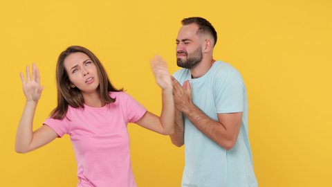 Young actors couple man woman in basic t-shirts posing isolated on yellow background studio. Start to play emotion like movie theater after clapperboard closing gesture fooling around fainting begging