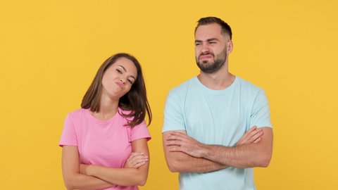 Young sad exhausted boring couple friends bearded man woman 20s in basic t-shirts isolated on yellow background studio. People emotions lifestyle concept. Look at camera wait folded hands sigh suspire