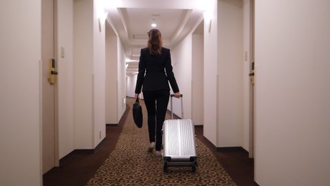 Business woman with small trolley case and laptop bag walk at corridor, super slow motion shot. Moving camera follow behind. Lady leave or arrive, go with confidence at long passage