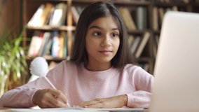 Happy indian latin girl school pupil distance learning, studying online at virtual class with teacher tutor by video conference call, watching tv lesson on laptop computer at home, in classroom. - Powered by Shutterstock - Get 15% off with code: PIKWIZARD15