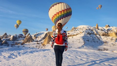 Woman rising her hands and looking on flight hot air balloons in Cappadocia