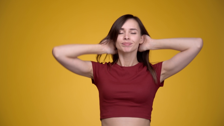 Young attractive cheerful woman playing with her hair. Yellow background.