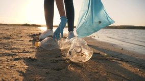 Teamwork cleaning plastic on the beach. Volunteers collect trash in a trash bag. Plastic pollution and environmental problem concept. Voluntary cleaning of nature from plastic. Greening the planet - Powered by Shutterstock - Get 15% off with code: PIKWIZARD15