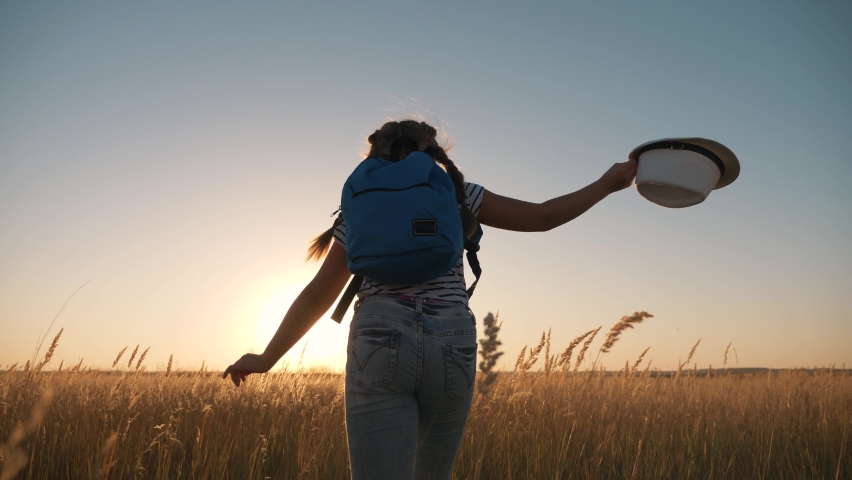 Happy girl runs with a backpack to success in the park. The girl dreams of success. Happy child is a winner. Child's dream and success concept. Winning the game in the park. Schoolgirl with a backpack