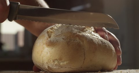 
Man Cutting a Piece of Bread with a Knife in the Kitchen on a Sunny Day Shot on Red Camera